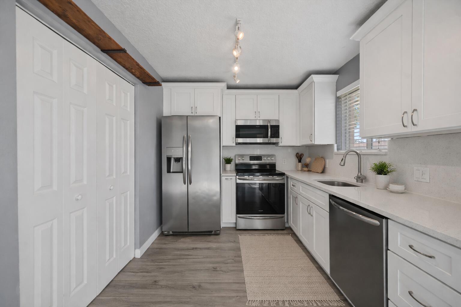 a kitchen with stainless steel appliances granite countertop a refrigerator a stove top oven a sink and dishwasher