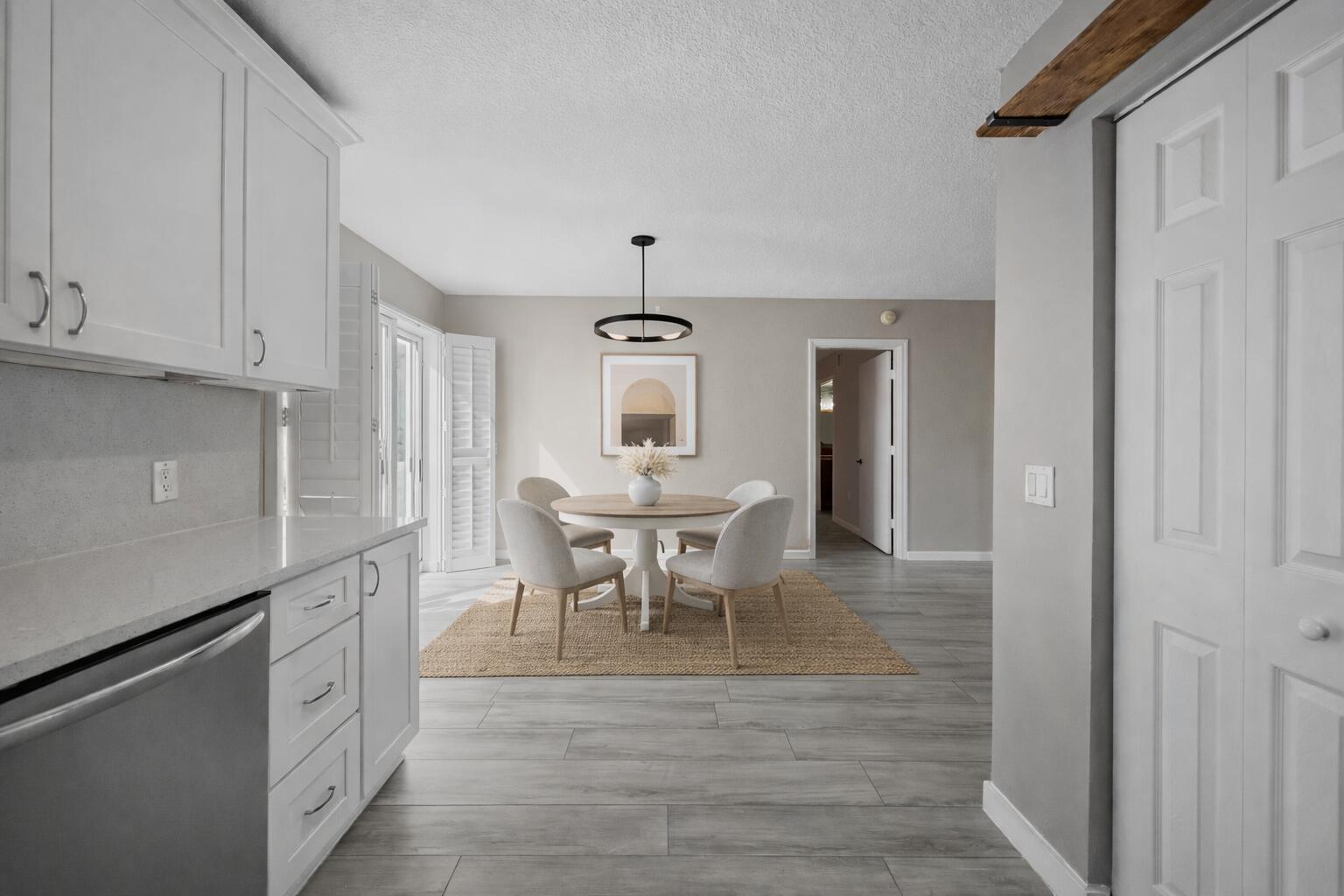 3486 Briar Bay Boulevard, Unit 101 West Palm Beach, FL 33411 - Photo 12 of 46 a dining room with wooden floor a chandelier a wooden table and chairs