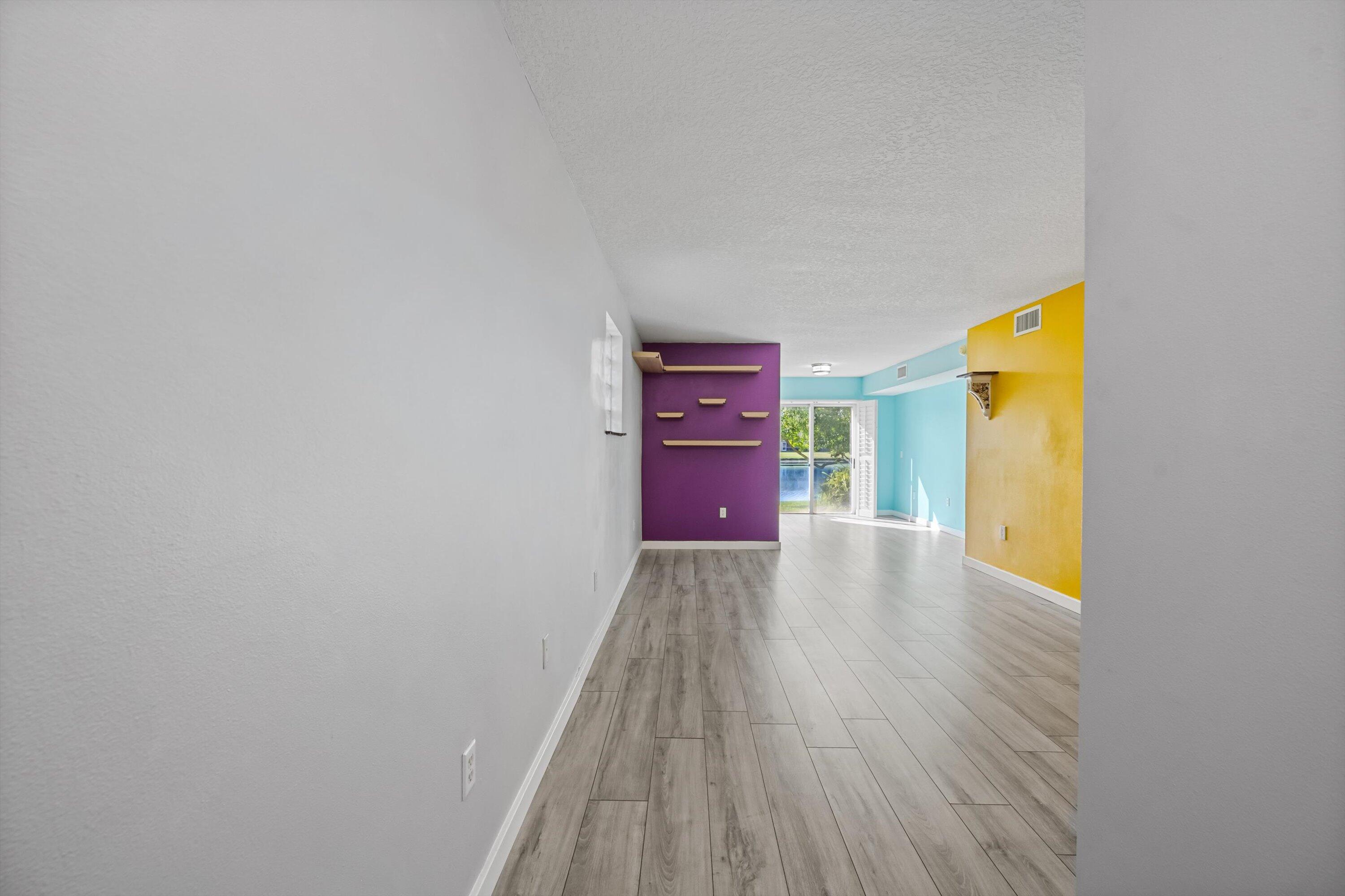 3486 Briar Bay Boulevard, Unit 101 West Palm Beach, FL 33411 - Photo 6 of 46 a view of an empty room with wooden floor and a window