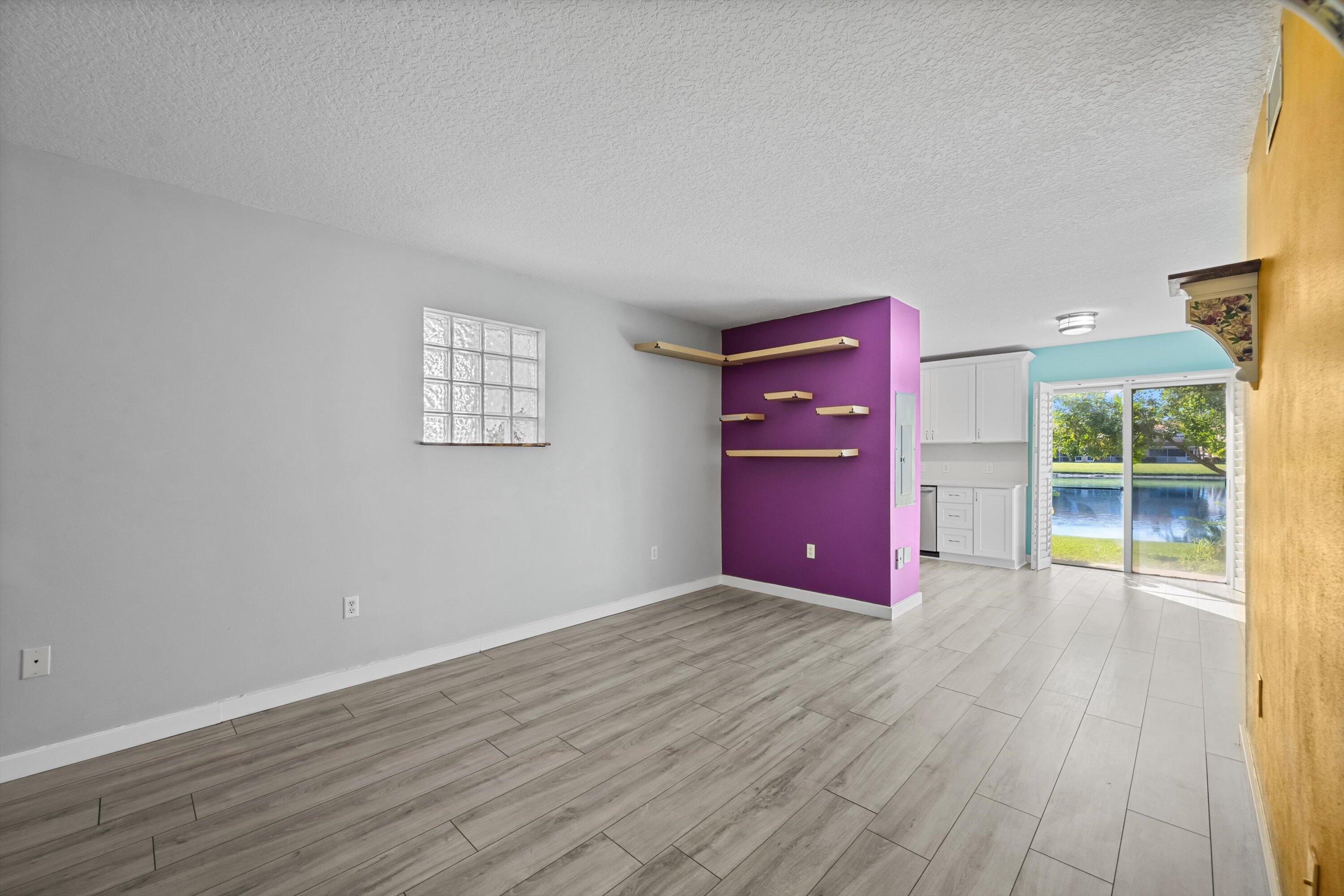 3486 Briar Bay Boulevard, Unit 101 West Palm Beach, FL 33411 - Photo 8 of 46 an empty room with wooden floor and windows