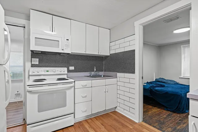 a kitchen with a stove white cabinets and a sink