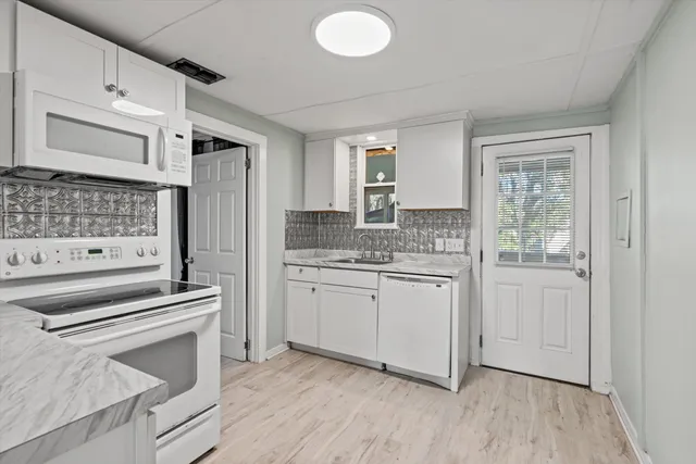 a kitchen with granite countertop white cabinets and white appliances