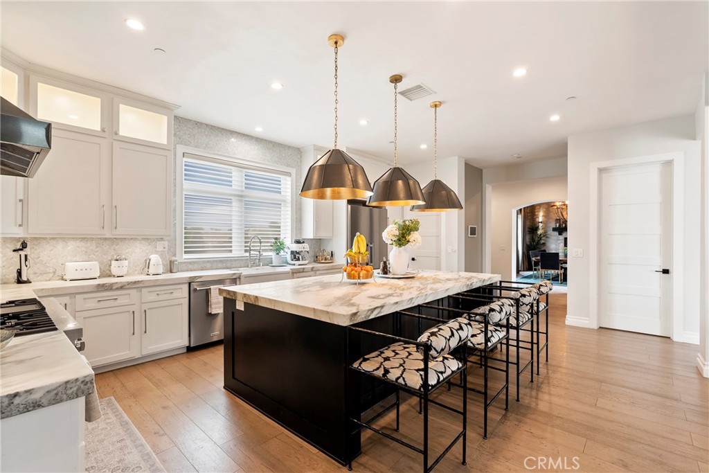 27716 Sycamore Mesa Road Temecula, CA 92590 - Photo 19 of 73 a kitchen with stainless steel appliances granite countertop a stove a sink dishwasher a dining table and chairs with wooden floor