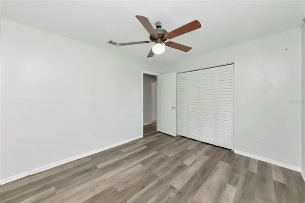 an empty room with wooden floor ceiling fan and windows