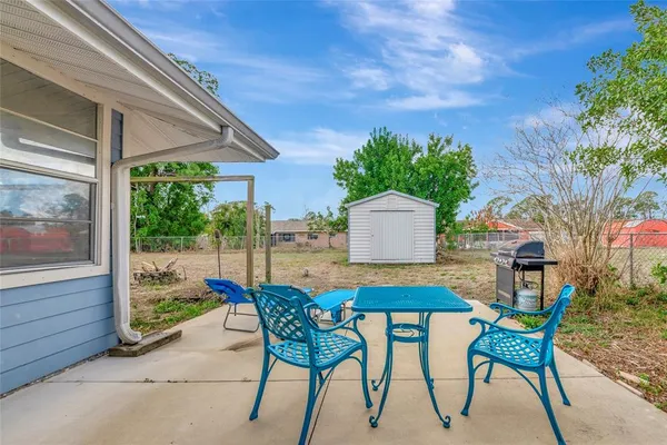 a patio with a table and chairs and potted plants