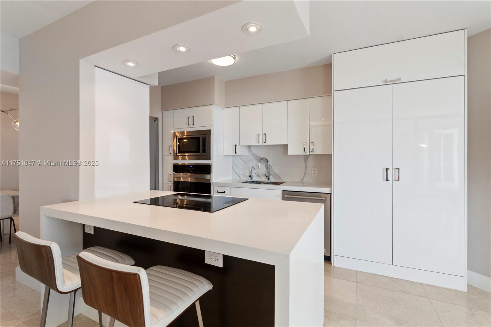 4779 Collins Avenue, Unit 2204 Miami Beach, FL 33140 - Photo 16 of 58 a kitchen with a sink a stove a refrigerator and white cabinets