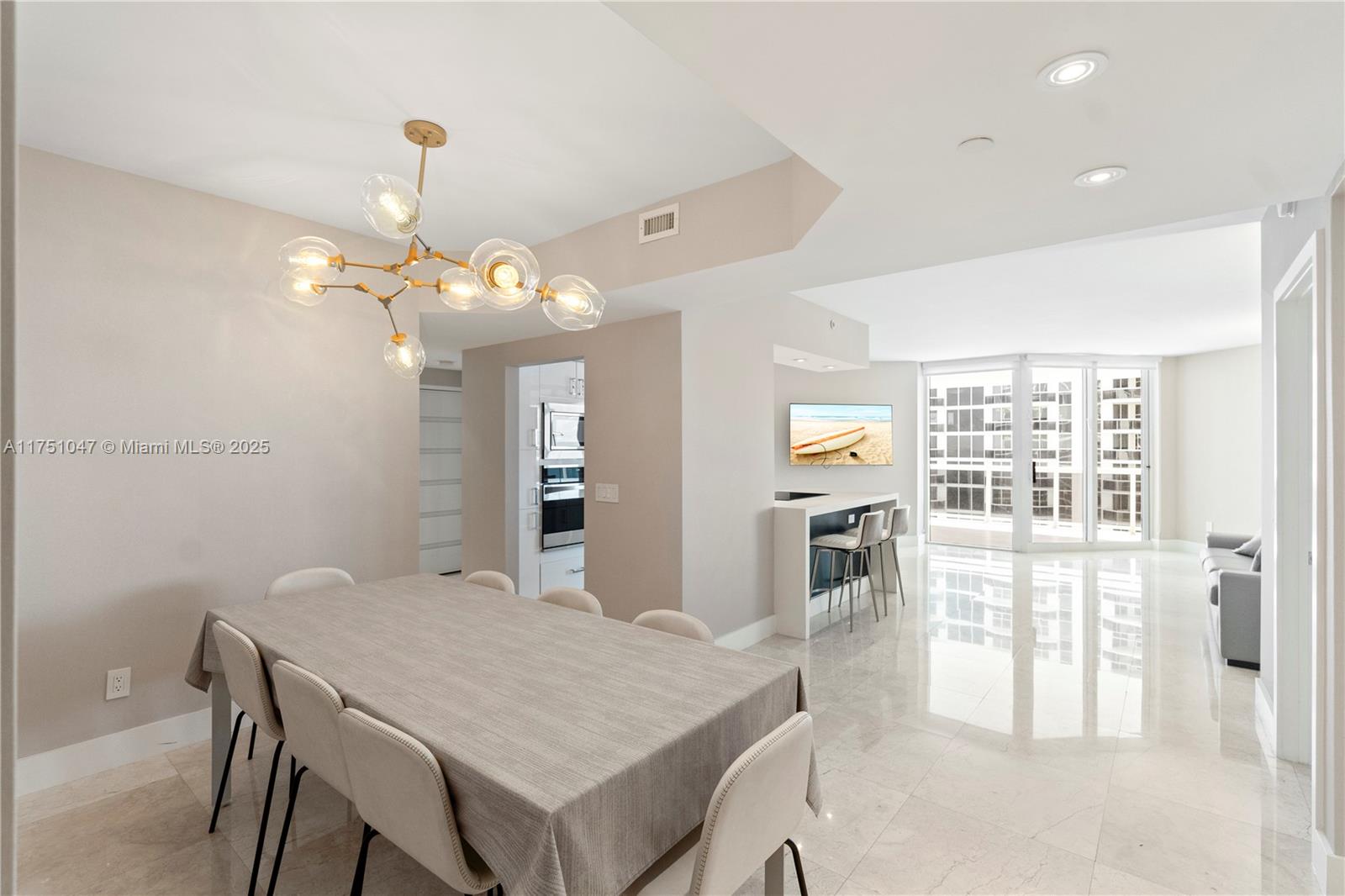 4779 Collins Avenue, Unit 2204 Miami Beach, FL 33140 - Photo 10 of 58 a view of a dining room with furniture wooden floor and chandelier
