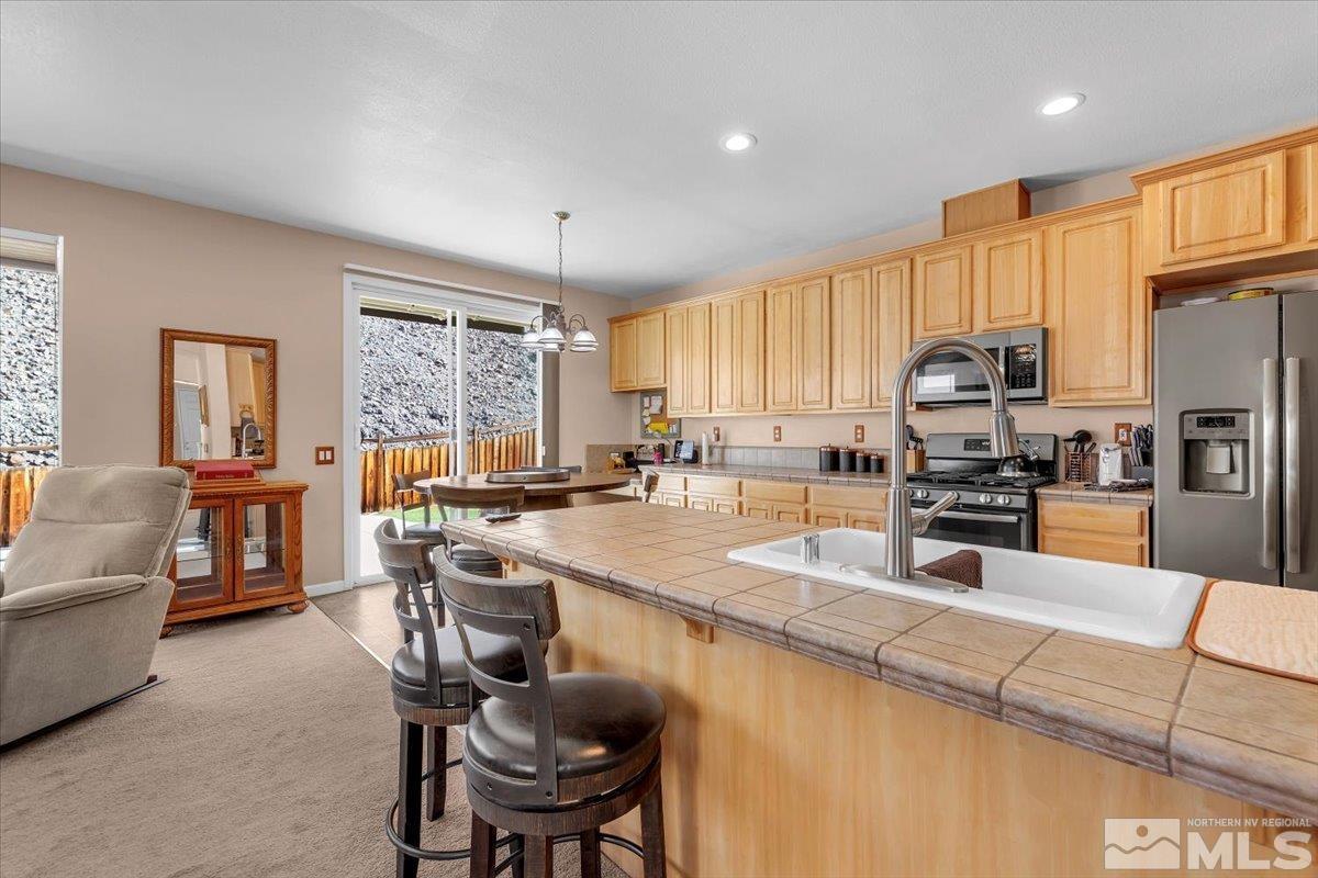 5670 Falcon Ridge Court Sparks, NV 89436 - Photo 13 of 40 a kitchen with stainless steel appliances granite countertop a stove top oven a sink dishwasher a dining table and chairs with wooden floor