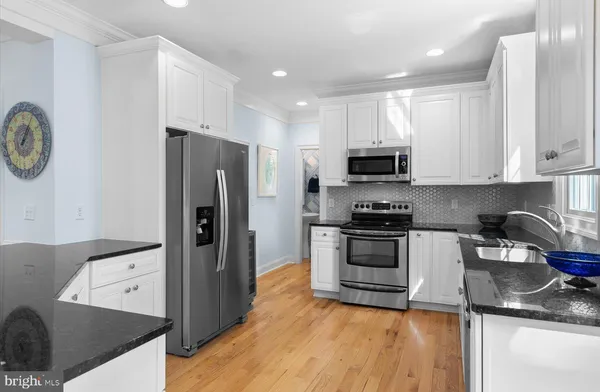 a kitchen with granite countertop a refrigerator stove and microwave