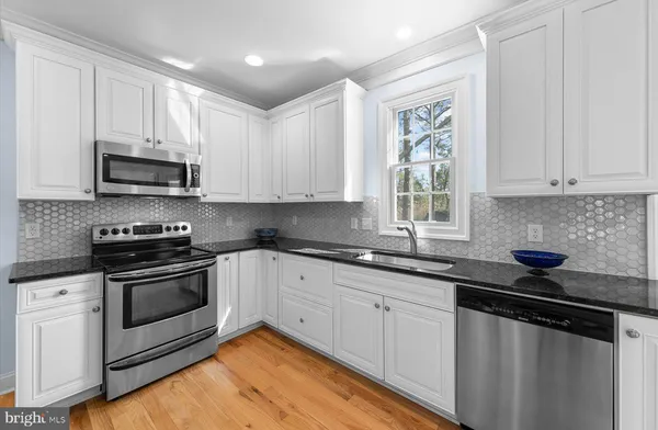 a kitchen with stainless steel appliances granite countertop a sink a stove a microwave and cabinets