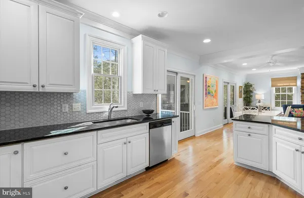 a kitchen with stainless steel appliances granite countertop white cabinets sink and window