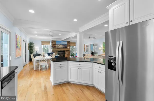 a kitchen with stainless steel appliances granite countertop a refrigerator a sink a stove and white cabinets with wooden floor