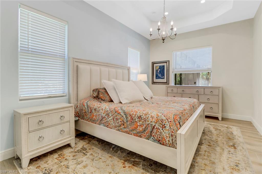 421 35th Avenue Northeast Naples, FL 34120 - Photo 19 of 39 a bedroom with a large bed and a chandelier