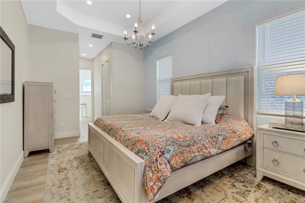421 35th Avenue Northeast Naples, FL 34120 - Photo 20 of 39 a bedroom with a large bed and a chandelier