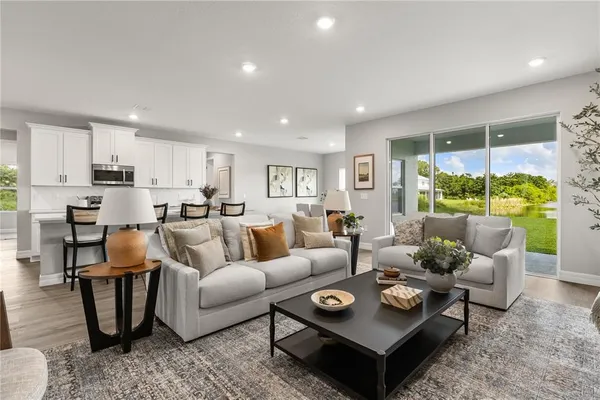 a living room with furniture kitchen view and a large window