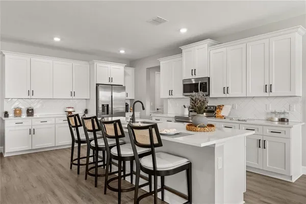 a kitchen with a dining table chairs white stainless steel appliances and cabinets