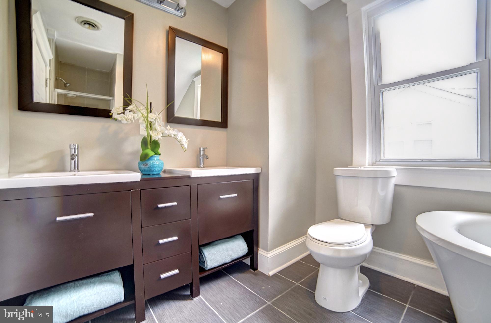 4008 Ridgecroft Road Baltimore, MD 21206 - Photo 11 of 17 a bathroom with a toilet a sink a mirror and a window
