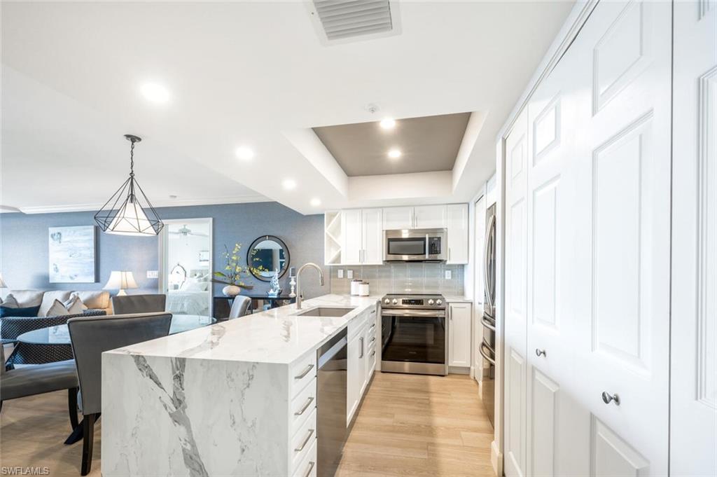 6849 Grenadier Boulevard, Unit 503 Naples, FL 34108 - Photo 11 of 50 a kitchen with stainless steel appliances a stove a sink a microwave and a refrigerator