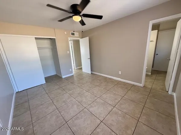 an empty room with wooden floor and a ceiling fan