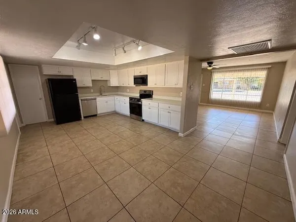 a large white kitchen with a sink a counter top space and stainless steel appliances