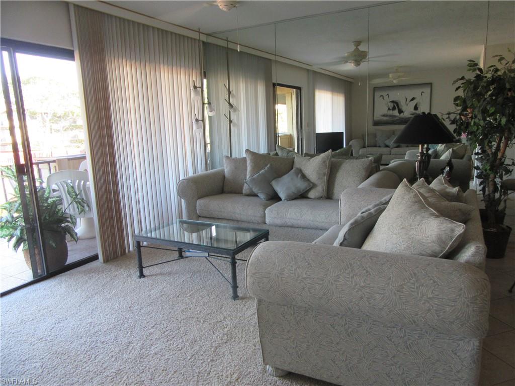 600 Neapolitan Way, Unit 211 Naples, FL 34103 - Photo 2 of 16 a living room with furniture and a large window