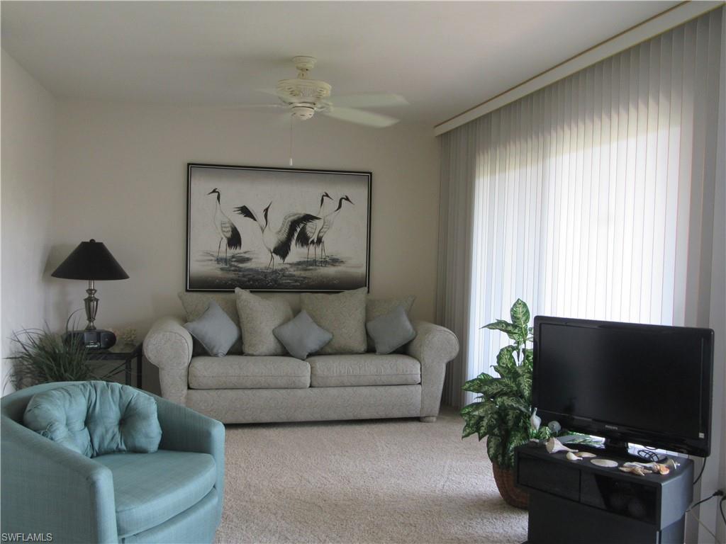 600 Neapolitan Way, Unit 211 Naples, FL 34103 - Photo 3 of 16 a living room with furniture and a flat screen tv