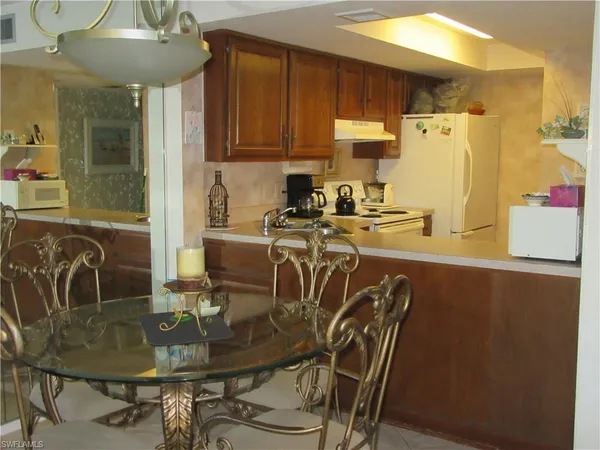 a kitchen with stainless steel appliances granite countertop a table chairs and a refrigerator
