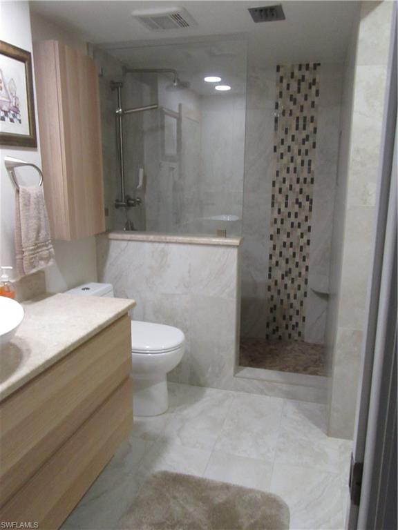 600 Neapolitan Way, Unit 211 Naples, FL 34103 - Photo 6 of 16 a bathroom with a sink a toilet and shower