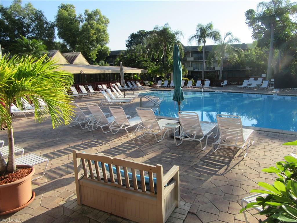 600 Neapolitan Way, Unit 211 Naples, FL 34103 - Photo 9 of 16 a view of a patio with table and chairs with wooden floor and fence