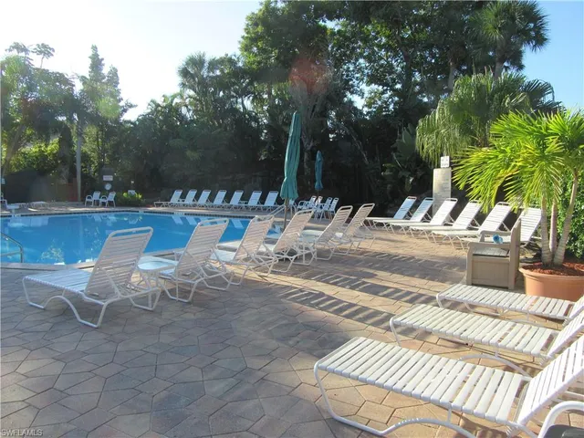 a view of swimming pool with lounge chair and dinning table under an umbrella