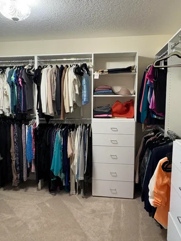 a view of walk in closet with clothes and shoes