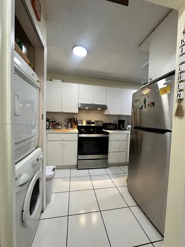 a kitchen with granite countertop a refrigerator sink stove and cabinets