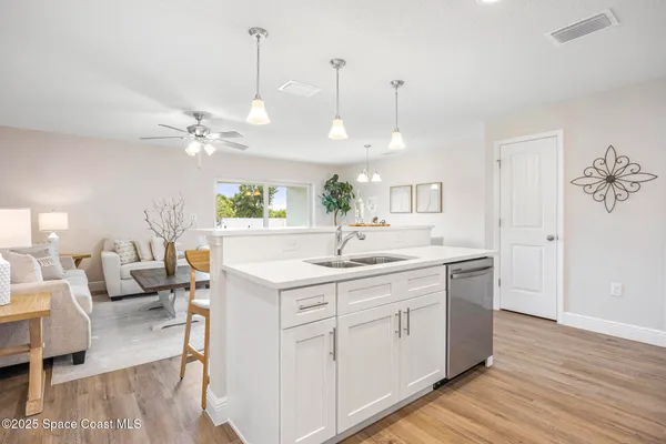 a large white kitchen with a lot of counter space and wooden floor