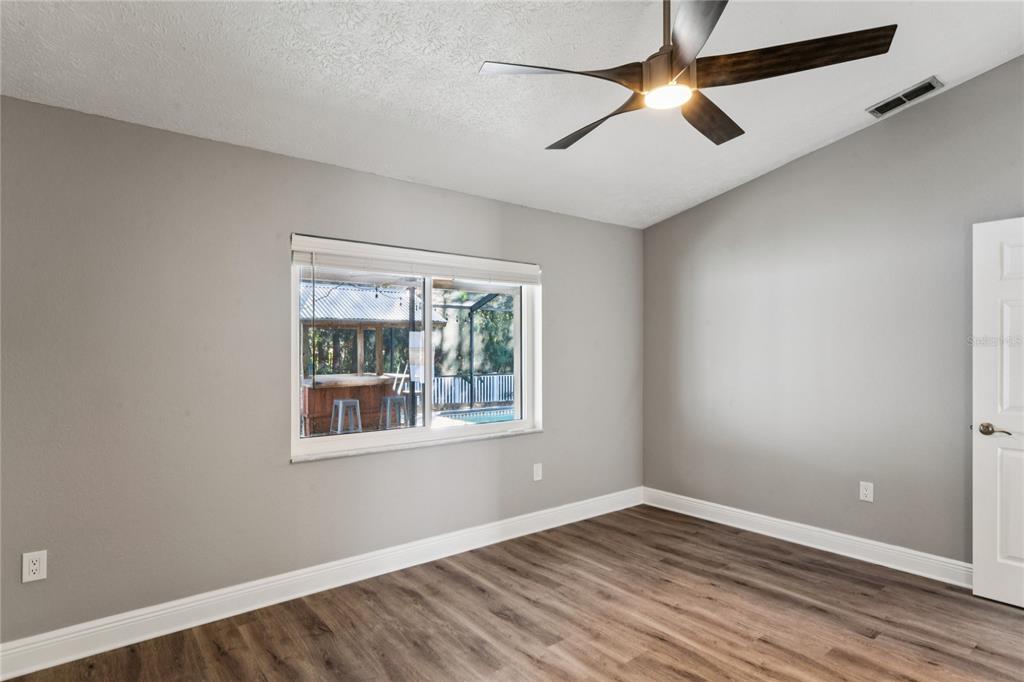 8357 Matthew Drive New Port Richey, FL 34653 - Photo 30 of 78 an empty room with wooden floor ceiling fan and windows