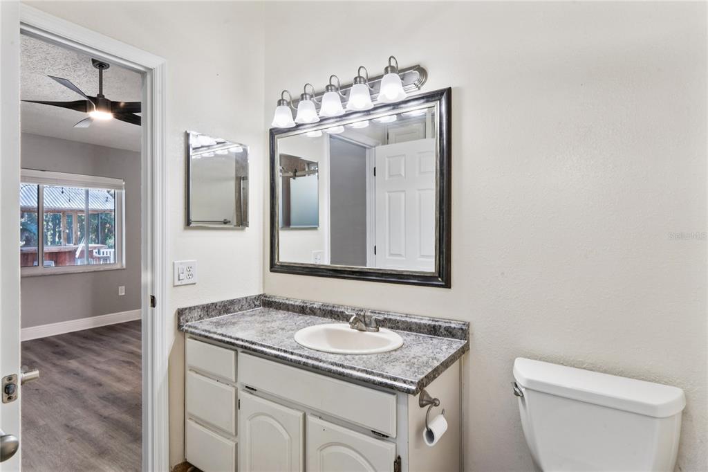 8357 Matthew Drive New Port Richey, FL 34653 - Photo 34 of 78 a bathroom with a granite countertop sink a toilet and a mirror