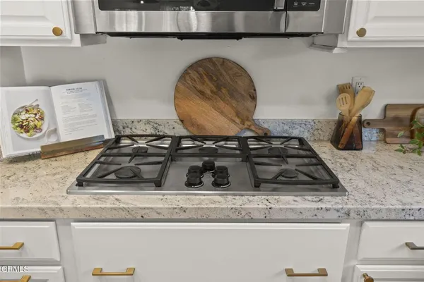 a kitchen with stainless steel appliances granite countertop white cabinets a stove top oven and refrigerator