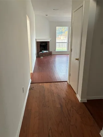 an empty room with wooden floor fireplace and windows