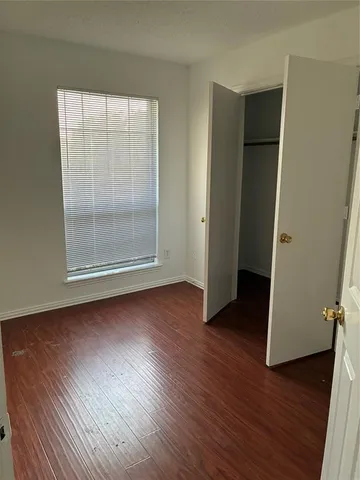 an empty room with wooden floor and window
