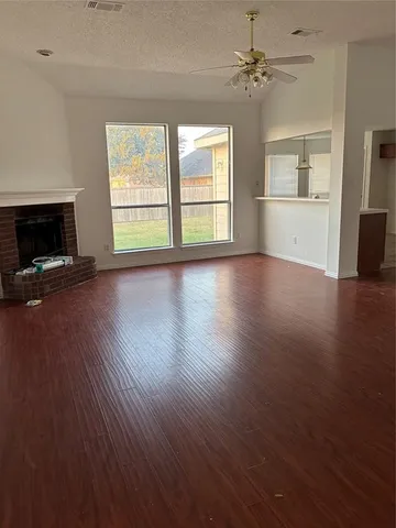 an empty room with wooden floor fireplace and windows