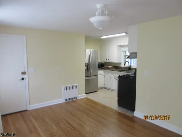 a kitchen with granite countertop a sink cabinets and wooden floor