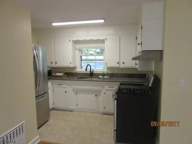 a kitchen with granite countertop a sink stove and refrigerator