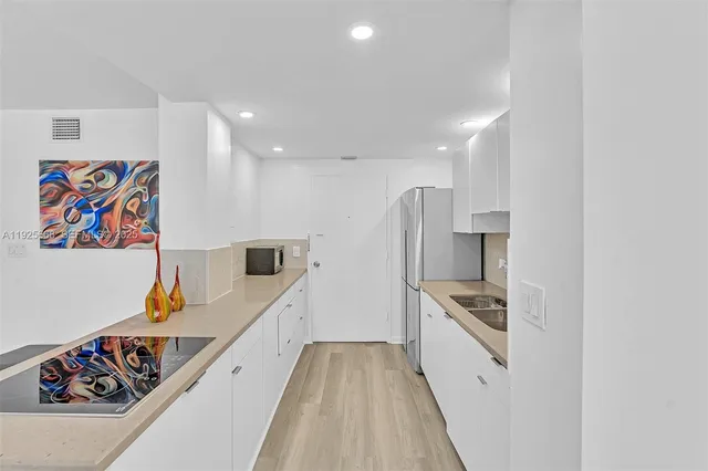 a kitchen with stainless steel appliances granite countertop a sink refrigerator and cabinets