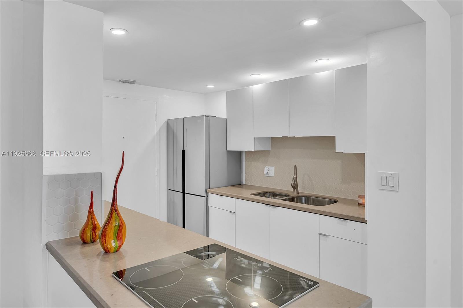 430 Golden Isles Drive, Unit 803 Hallandale Beach, FL 33009 - Photo 19 of 48 a kitchen with stainless steel appliances granite countertop a sink refrigerator and cabinets