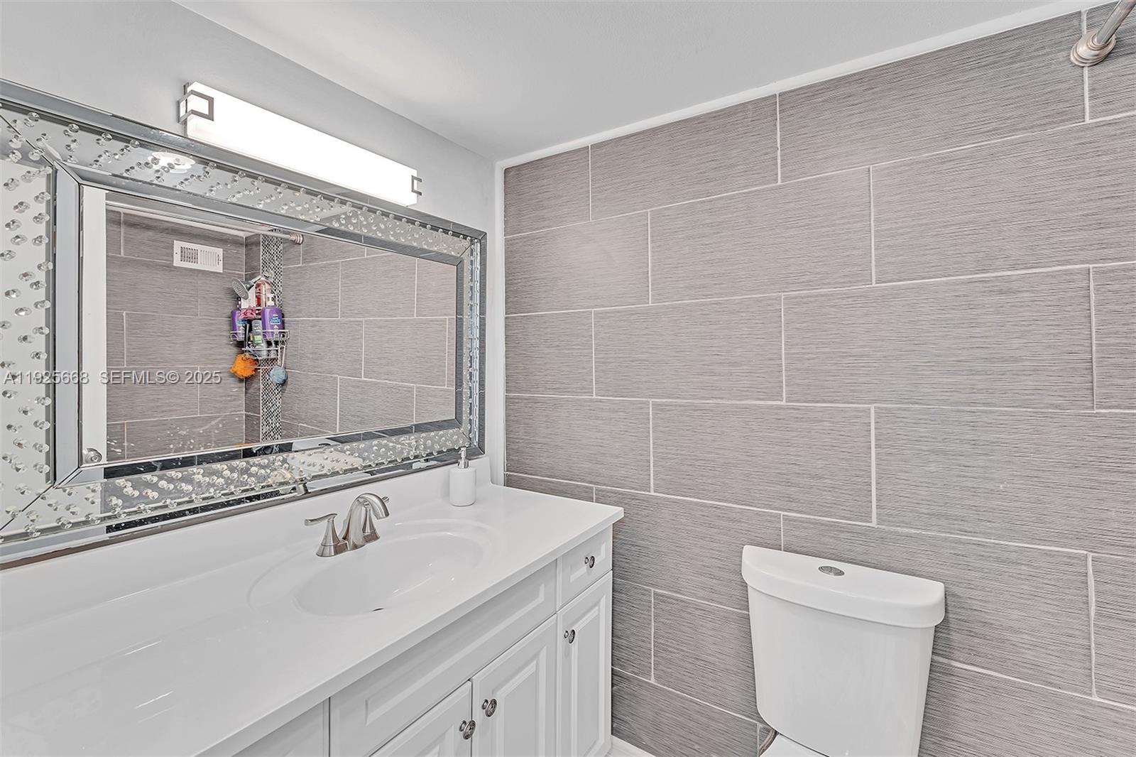 430 Golden Isles Drive, Unit 803 Hallandale Beach, FL 33009 - Photo 31 of 48 a bathroom with a sink a toilet and a mirror