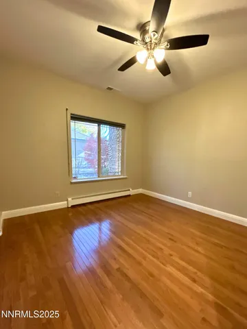 an empty room with wooden floor fan and windows