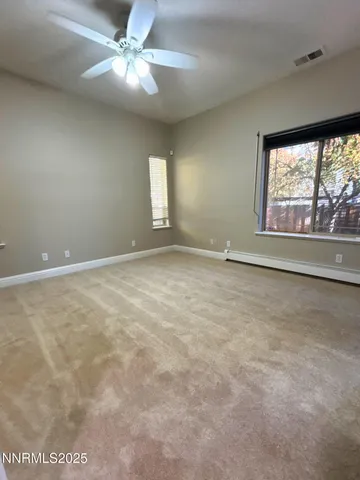 an empty room with windows and fan