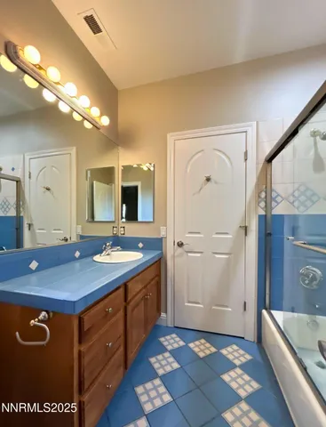 a bathroom with a granite countertop sink a mirror and a shower