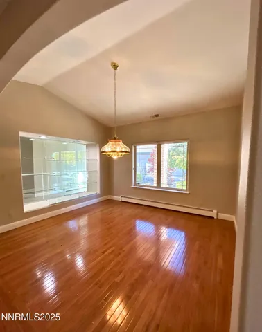 a view of empty room with wooden floor and fan