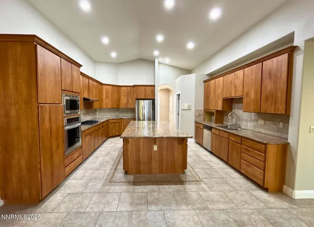 a large kitchen with kitchen island granite countertop wooden cabinets a sink and stainless steel appliances