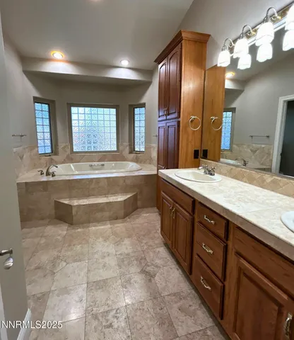 a spacious bathroom with a tub sink and a mirror